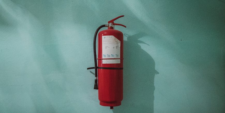 red fire extinguisher on green wall